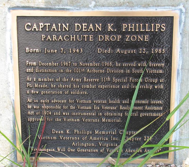 A bronze plaque set in stone reading: Captain Dean K. Phillips Parachute Drop Zone, born June 7 1943, died August 22 1985, followed by his service with the 101st Airborne Division and his work on veterans legislation and the Vietnam Veterans Memorial.